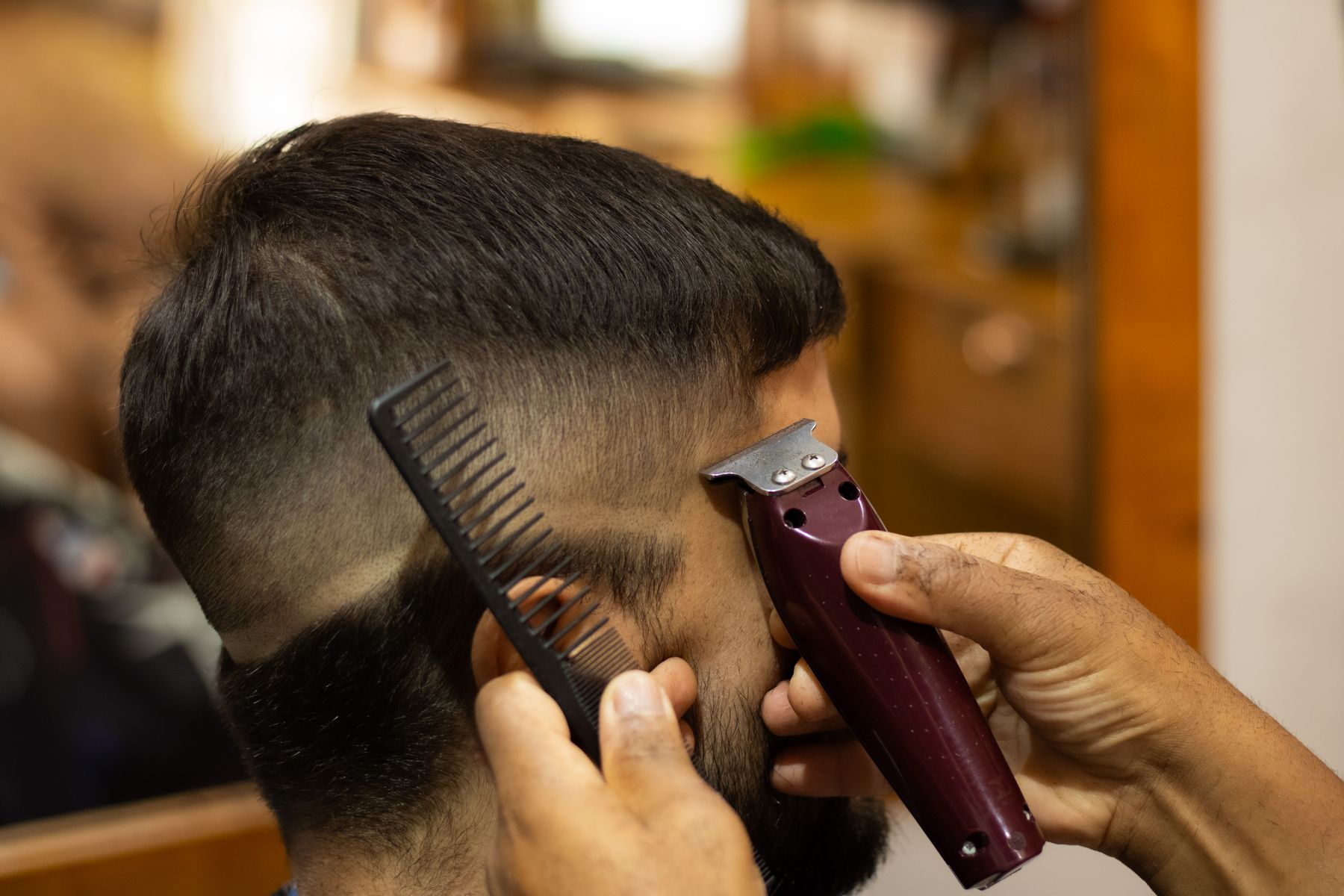 Barber using clippers and a comb for a precise cut