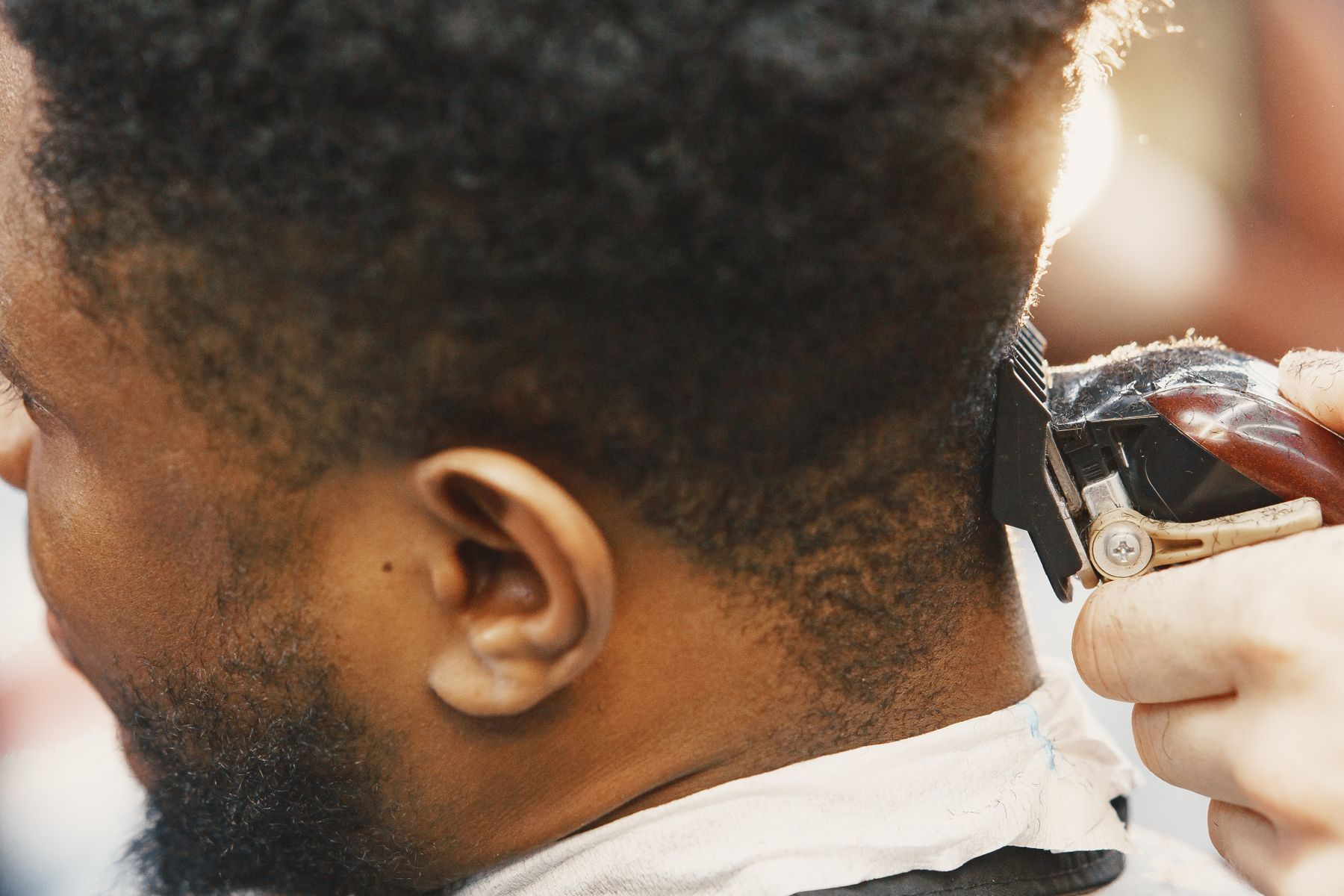 Barber trimming the back of a man's hair with clippers